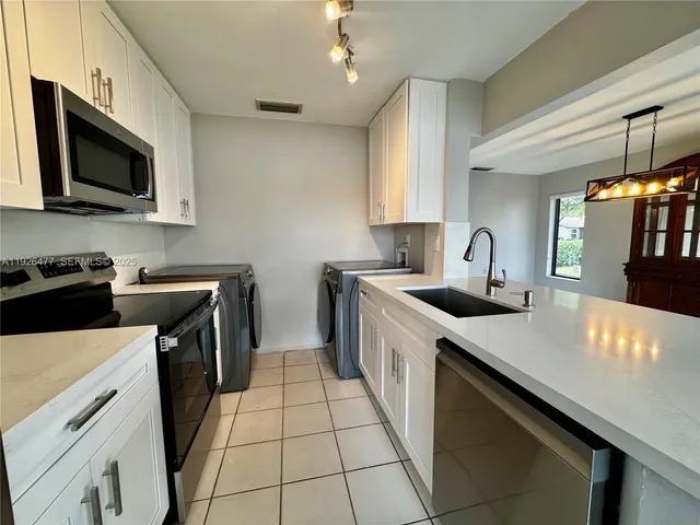 a kitchen with a sink a stove top oven a counter space and cabinets