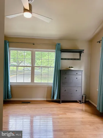 a view of empty room with wooden floor and fan