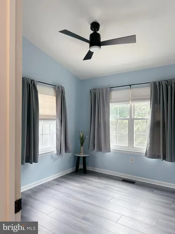 a view of an empty room with a window and wooden floor