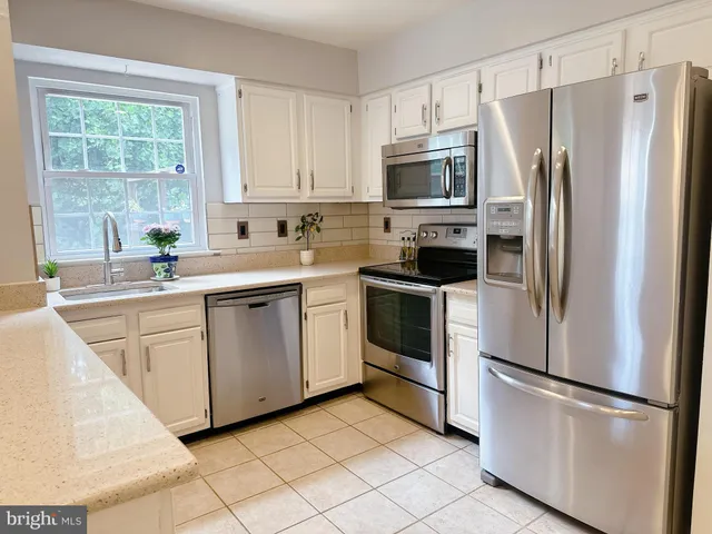 a kitchen with white cabinets stainless steel appliances and window
