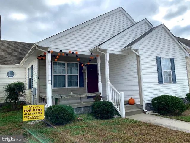 a view of small white house with a yard and plants