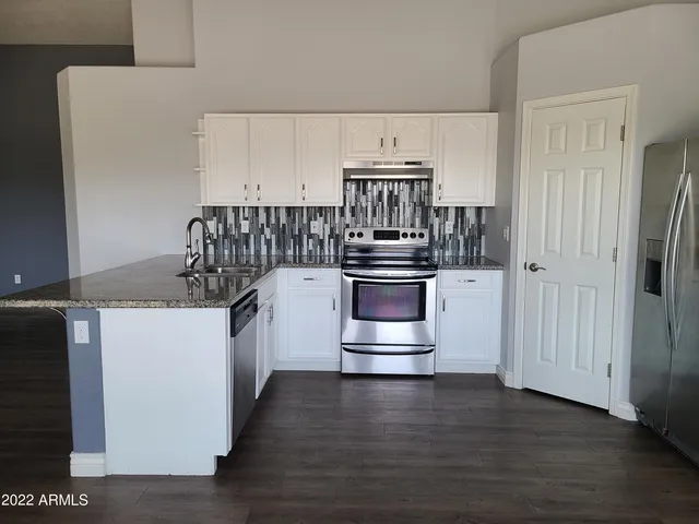 a kitchen with stainless steel appliances a refrigerator and white cabinets