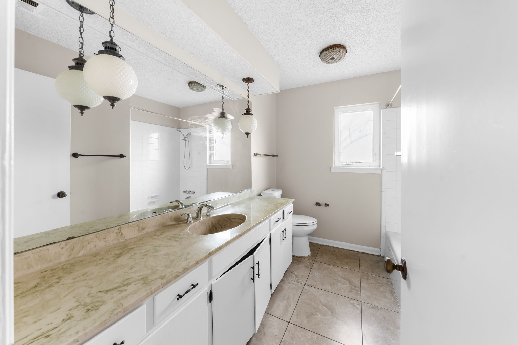 13203 Stillforest Street Austin, TX 78729 - Photo 19 of 33 a spacious bathroom with a granite countertop sink a toilet a mirror and vanity
