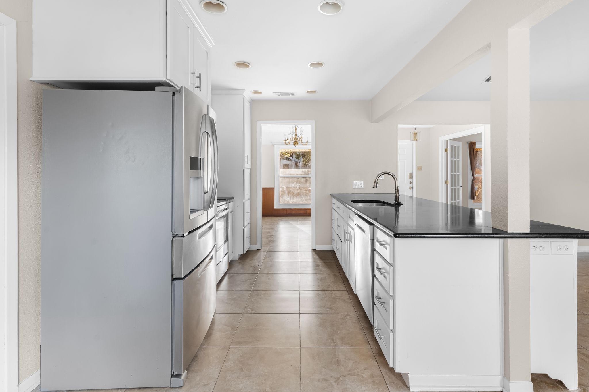 13203 Stillforest Street Austin, TX 78729 - Photo 23 of 33 Kitchen with stainless steel appliances, white cabinets, dark stone counters, a peninsula, and light tile patterned floors
