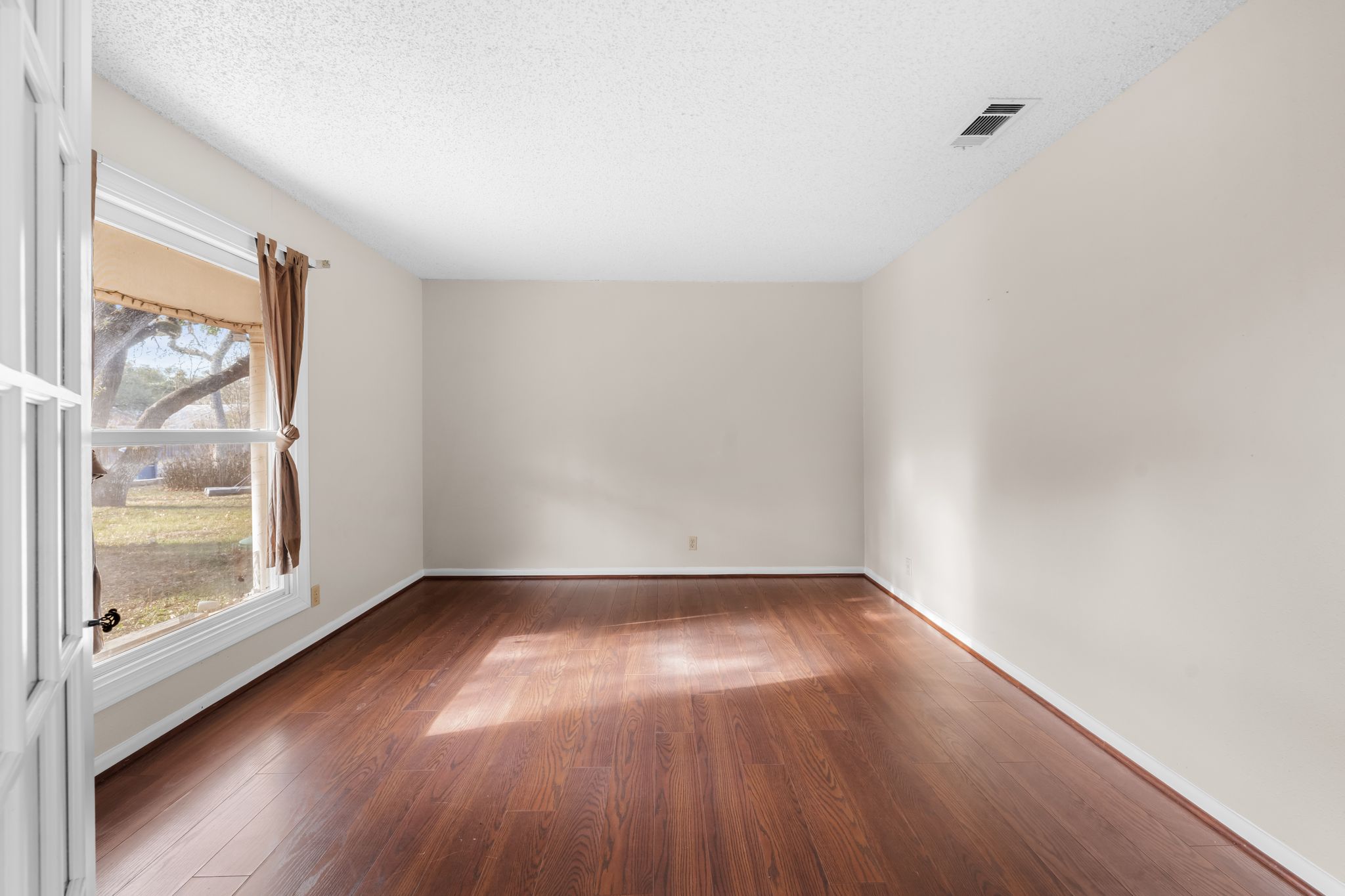 13203 Stillforest Street Austin, TX 78729 - Photo 25 of 33 a view of an empty room with wooden floor and a window