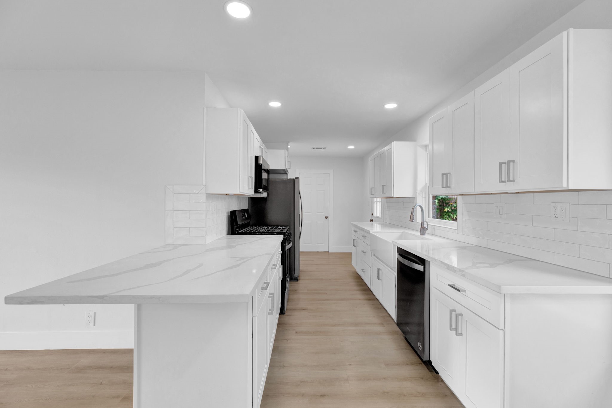 3511 Arbor Street Houston, TX 77004 - Photo 8 of 17 a large kitchen with stainless steel appliances kitchen island a sink dishwasher a stove and white cabinets with wooden floor