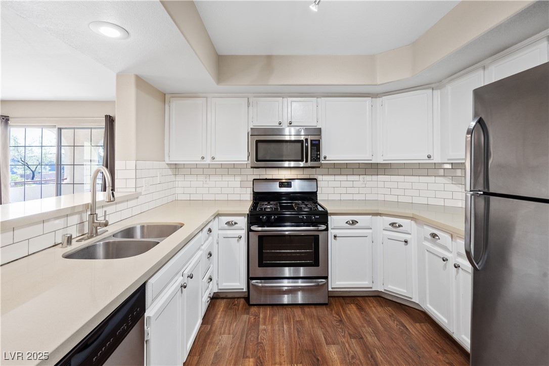 7950 West Flamingo Road, Unit 1039 Las Vegas, NV 89147 - Photo 11 of 26 Kitchen with stainless steel appliances, white cabinets, dark wood finished floors, backsplash, and recessed lighting