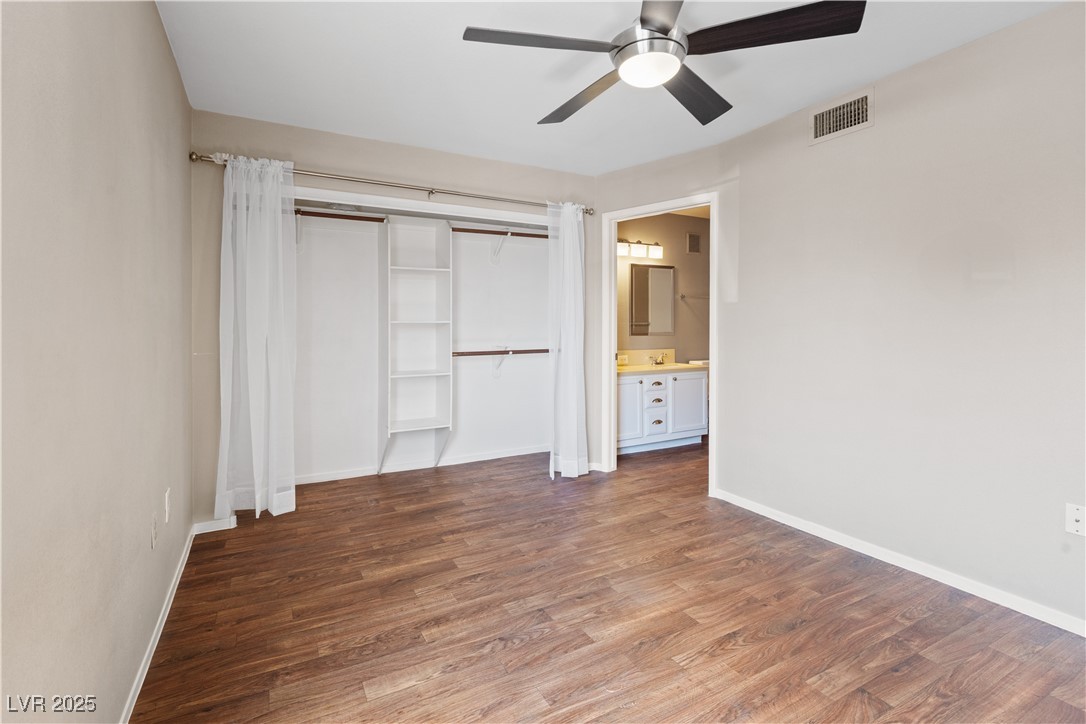 7950 West Flamingo Road, Unit 1039 Las Vegas, NV 89147 - Photo 14 of 26 Unfurnished bedroom with dark wood finished floors, a closet, ceiling fan, and connected bathroom