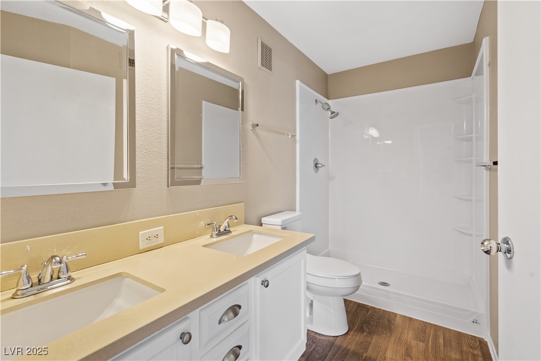 7950 West Flamingo Road, Unit 1039 Las Vegas, NV 89147 - Photo 15 of 26 Bathroom featuring dark wood-type flooring, double vanity, and a shower stall