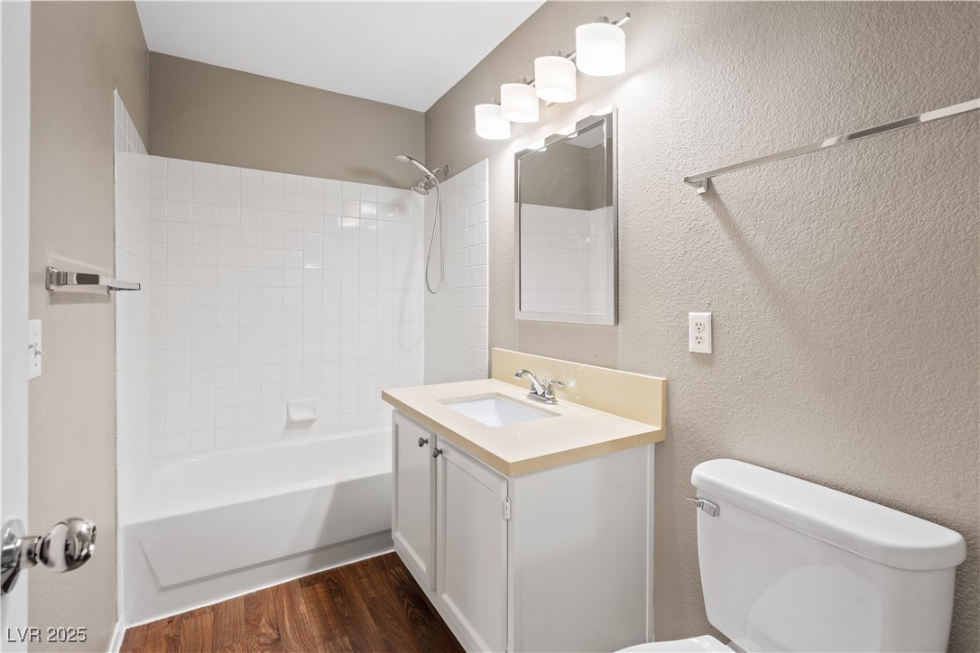 7950 West Flamingo Road, Unit 1039 Las Vegas, NV 89147 - Photo 18 of 26 Full bath with vanity, shower / bath combination, a textured wall, and dark wood-type flooring