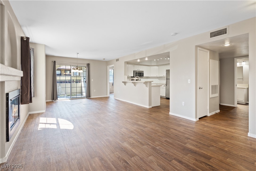 7950 West Flamingo Road, Unit 1039 Las Vegas, NV 89147 - Photo 2 of 26 Unfurnished living room with a glass covered fireplace and dark wood finished floors