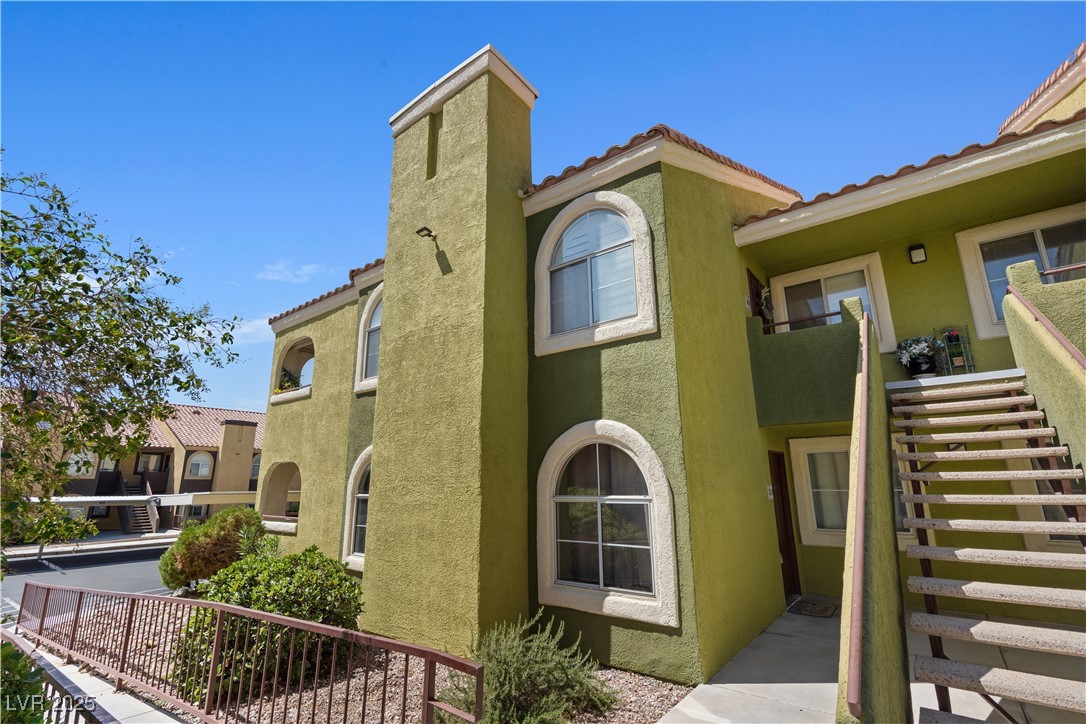 7950 West Flamingo Road, Unit 1039 Las Vegas, NV 89147 - Photo 22 of 26 View of property exterior featuring stucco siding, a tile roof, a balcony, and stairs
