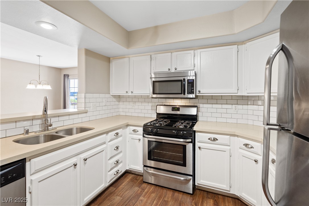 7950 West Flamingo Road, Unit 1039 Las Vegas, NV 89147 - Photo 3 of 26 Kitchen with appliances with stainless steel finishes, white cabinetry, dark wood finished floors, decorative light fixtures, and a chandelier