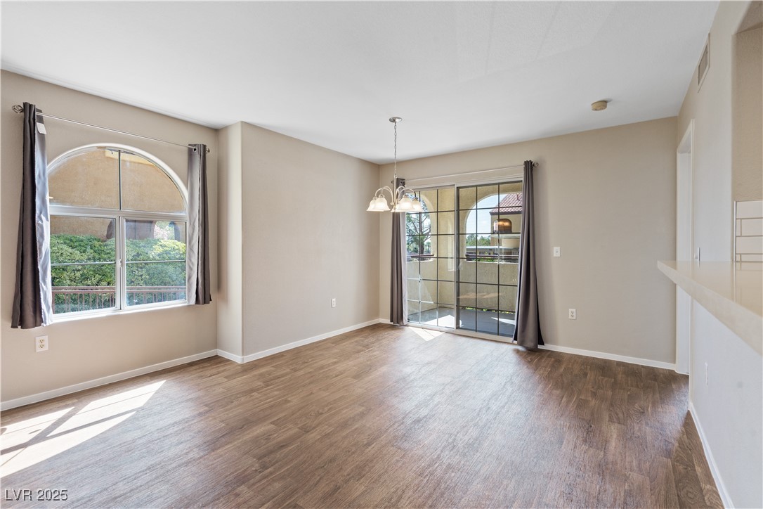 7950 West Flamingo Road, Unit 1039 Las Vegas, NV 89147 - Photo 7 of 26 Unfurnished dining area featuring a chandelier and dark wood-style flooring
