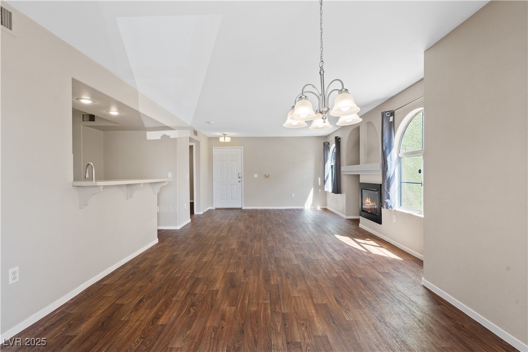 7950 West Flamingo Road, Unit 1039 Las Vegas, NV 89147 - Photo 8 of 26 Unfurnished dining area with dark wood-style floors, a chandelier, and a glass covered fireplace