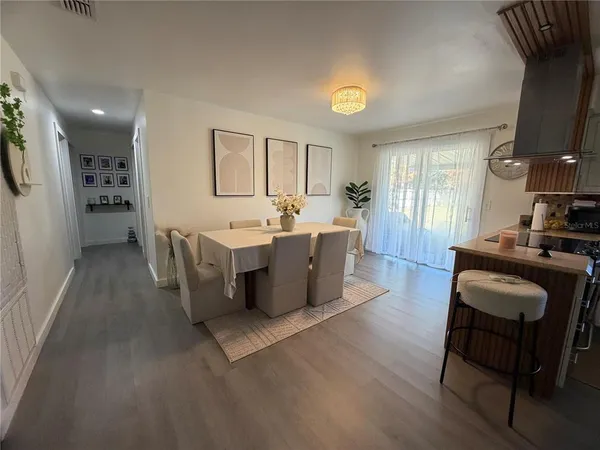 a living room with a couch and a dining table with wooden floor