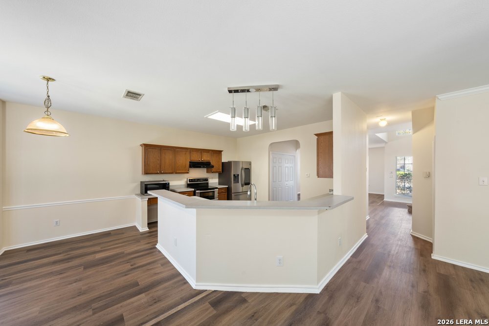 12319 Stable Rd Drive San Antonio, TX 78249 - Photo 12 of 34 a view of a kitchen with kitchen island a sink wooden floor and a refrigerator