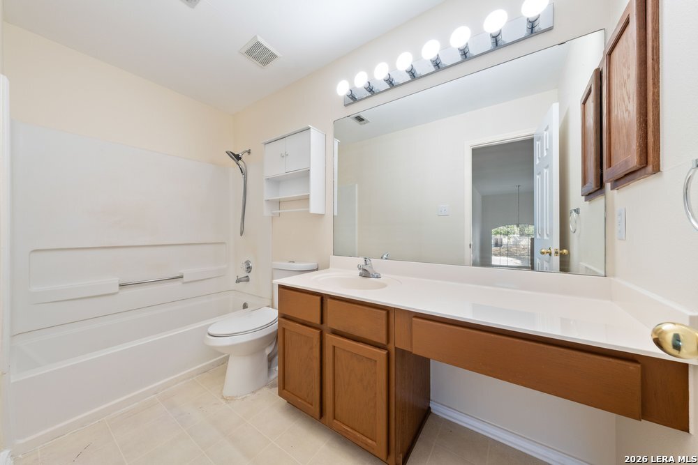 12319 Stable Rd Drive San Antonio, TX 78249 - Photo 19 of 34 a bathroom with a double vanity sink a toilet a mirror and bathtub