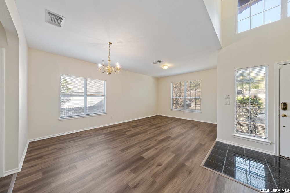 12319 Stable Rd Drive San Antonio, TX 78249 - Photo 6 of 34 an empty room with wooden floor chandelier and windows
