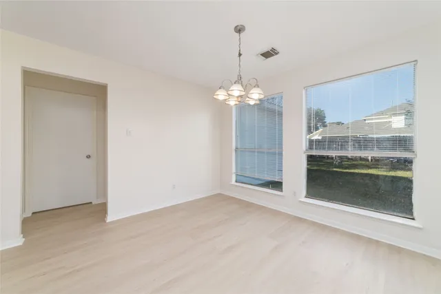 a view of a livingroom with a chandelier wooden floor and kitchen