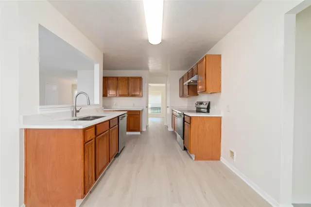 a large kitchen with stainless steel appliances granite countertop a sink and a stove with wooden floor