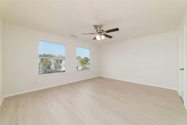 an empty room with windows and ceiling fan