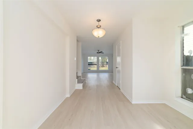 a view of a hallway with wooden floor and a bathroom