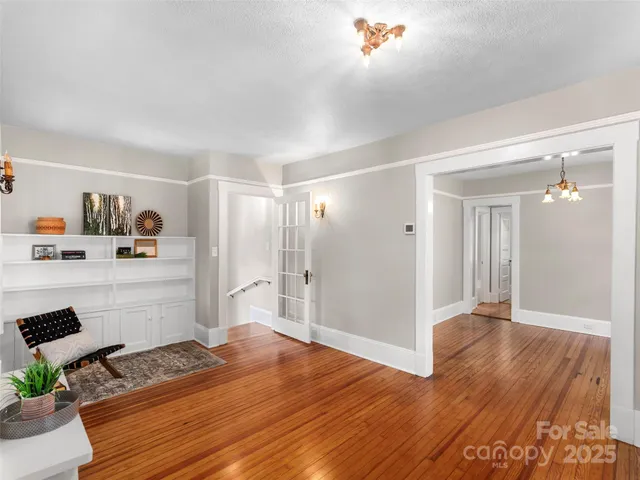 a room with kitchen island white cabinets and wooden floor