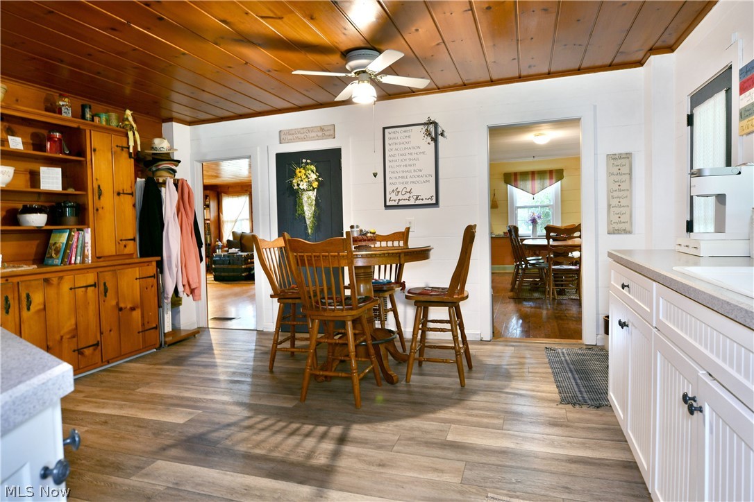8683 King Graves Road Northeast Warren, OH 44484 - Photo 8 of 50 Kitchen and dining area featuring wood-finish flooring, a wood-paneled ceiling, and white cabinetry with beadboard detailing