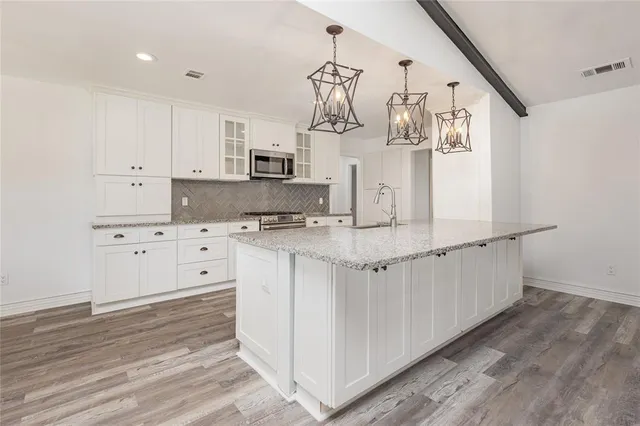 a kitchen with white cabinets and sink