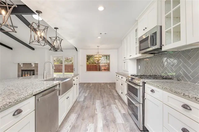 a large kitchen with stainless steel appliances granite countertop a stove and a sink