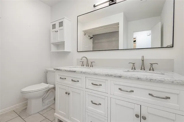 a bathroom with a granite countertop toilet sink and mirror