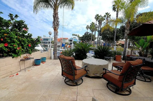 a view of a patio with dining table and chairs potted plants and palm trees