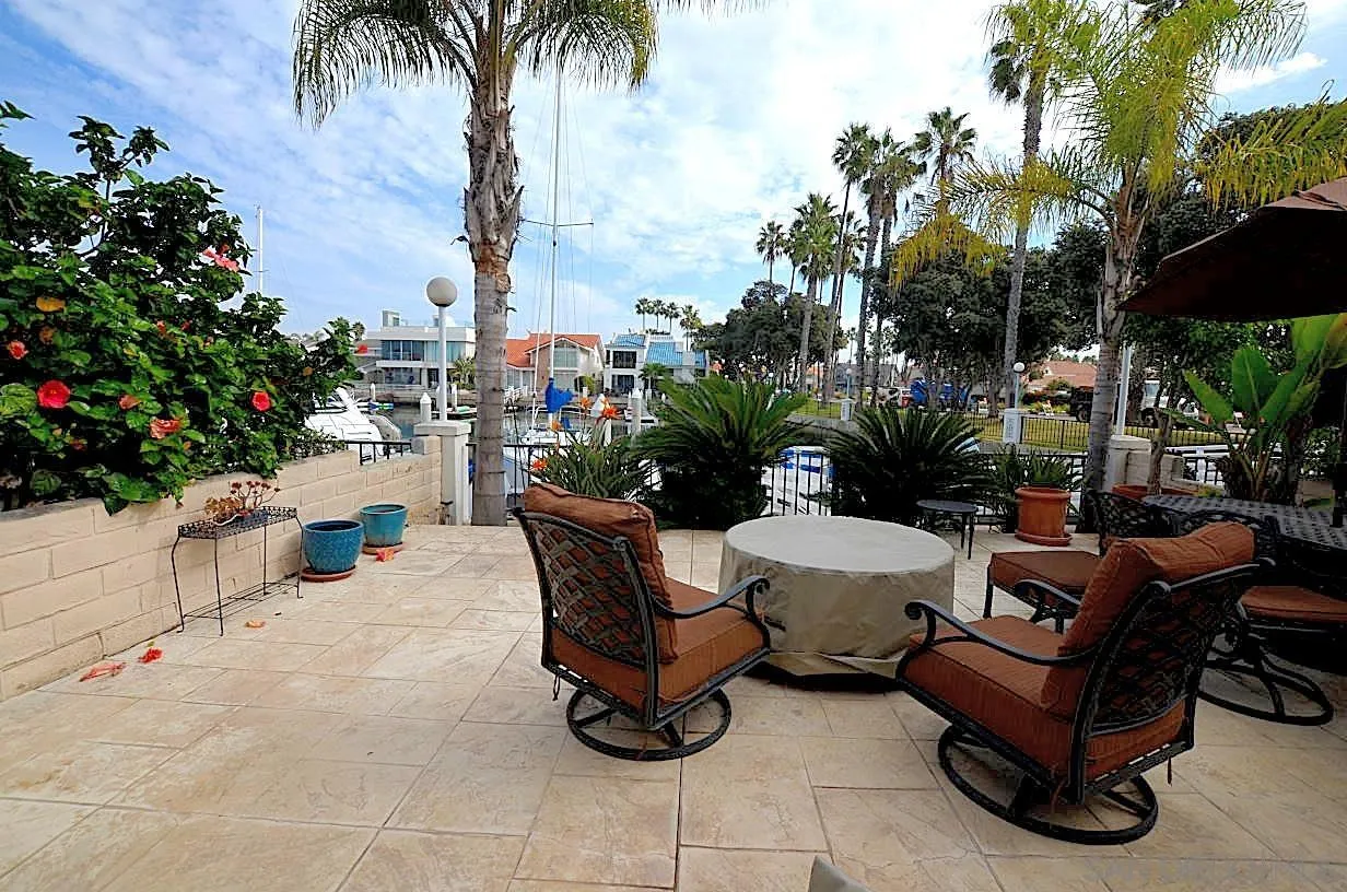 95 Port Of Spain Road Coronado, CA 92118 - Photo 31 of 40 a view of a patio with dining table and chairs potted plants and palm trees