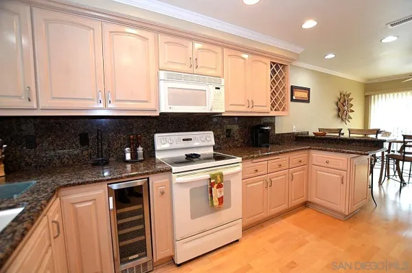 a kitchen with granite countertop a sink stove top oven and cabinets
