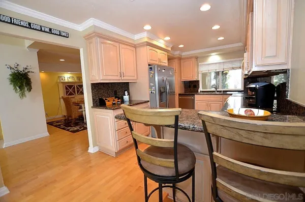 a kitchen with stainless steel appliances kitchen island granite countertop a table chairs and a refrigerator