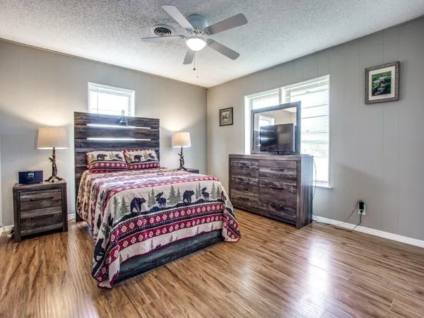 a bedroom with a bed a dresser and wooden floor