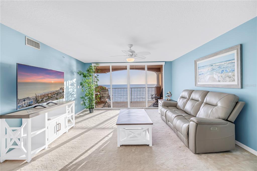 16326 Gulf Boulevard, Unit 308 Redington Beach, FL 33708 - Photo 13 of 44 a living room with furniture a flat screen tv and a floor to ceiling window