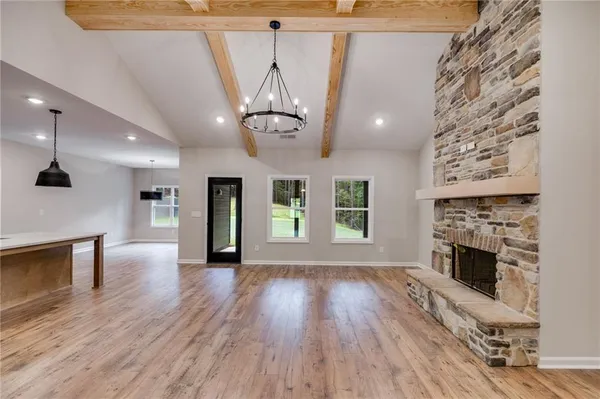 an empty room with wooden floor fireplace and windows