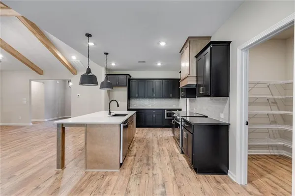 a kitchen with stainless steel appliances granite countertop a sink a stove and a wooden floors
