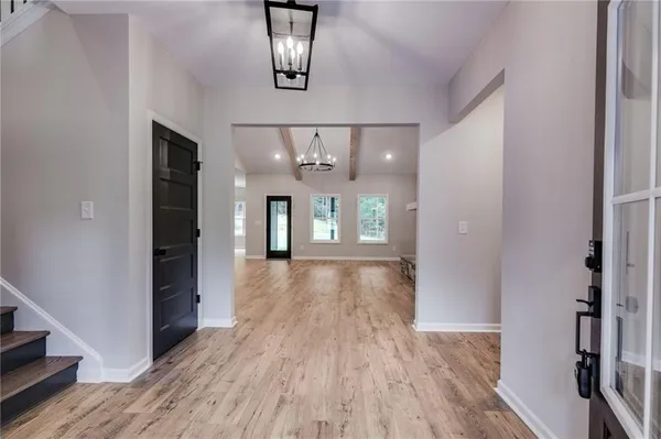 a view of a hallway with wooden floor and chandelier