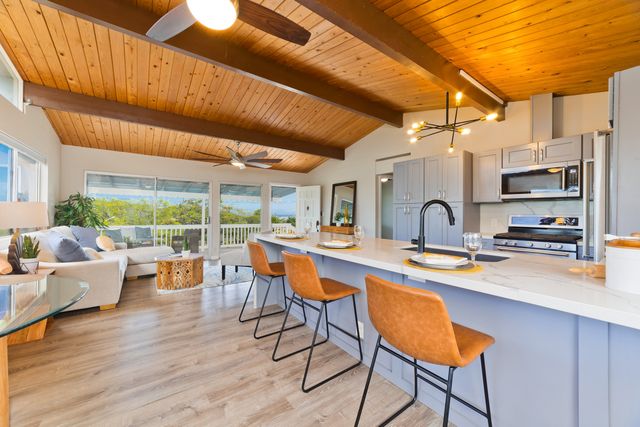 a dining hall with stainless steel appliances granite countertop a table chairs and a large window