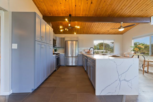 a kitchen with stainless steel appliances kitchen island granite countertop a refrigerator and cabinets