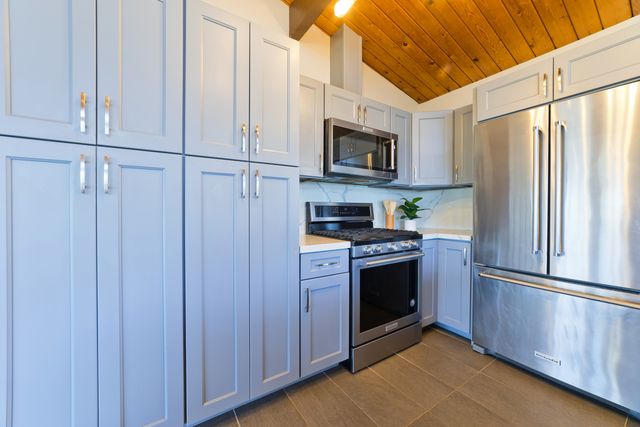 a kitchen with stainless steel appliances granite countertop a refrigerator a stove and a microwave