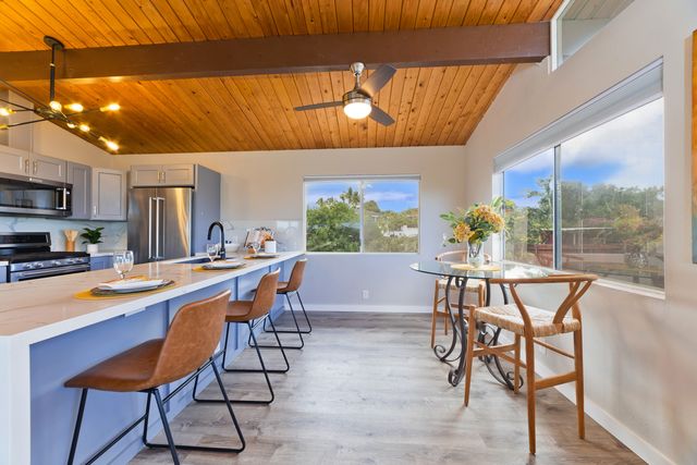 a dining room with stainless steel appliances a dining table and chairs with kitchen view