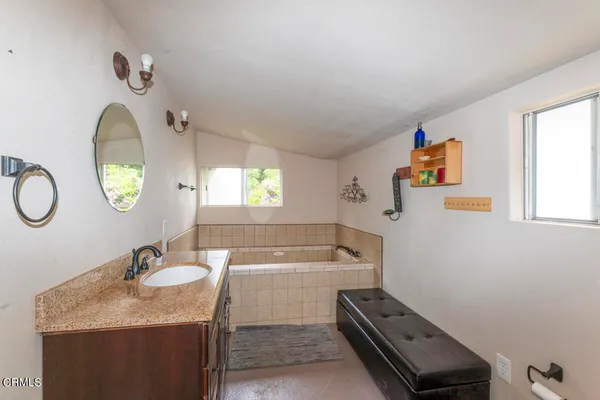 a bathroom with a granite countertop sink mirror and a bathtub
