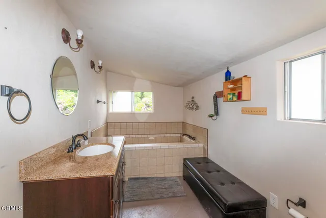 a bathroom with a granite countertop sink mirror and a bathtub