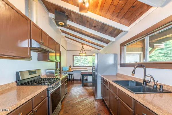 a kitchen with stainless steel appliances granite countertop a sink a stove and a wooden floors