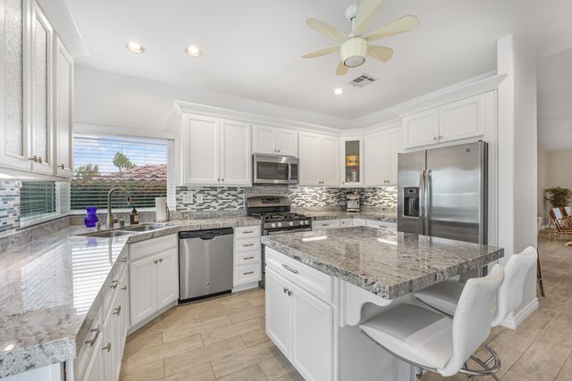 a kitchen with stainless steel appliances granite countertop a sink dishwasher stove top oven and refrigerator