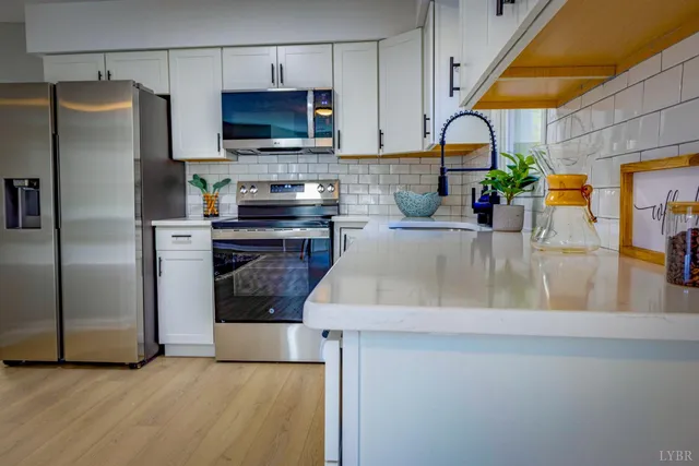 a kitchen with stainless steel appliances granite countertop a stove a sink and white cabinets
